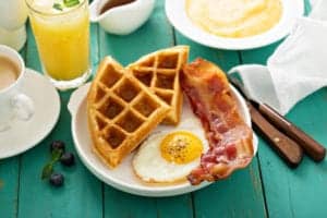 waffle, egg, bacon, orange juice, grits, and coffee